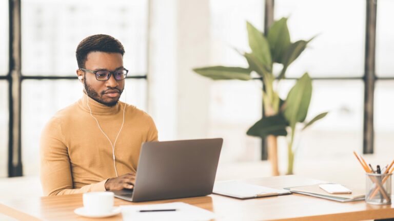 concentrated afro guy in eyewear typing on keyboar 4NQHTJN scaled 1 768x432