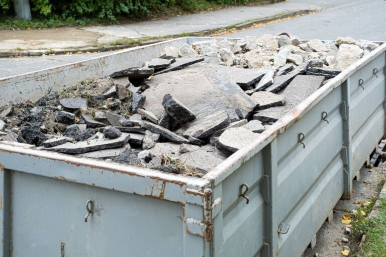 Big Overloaded dumpster waste container filled with pieces of removed asphalt construction waste near a road digging construction site 768x512
