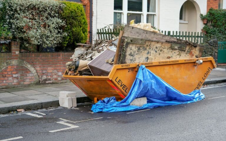 Large orange metal skip container in front house 768x480
