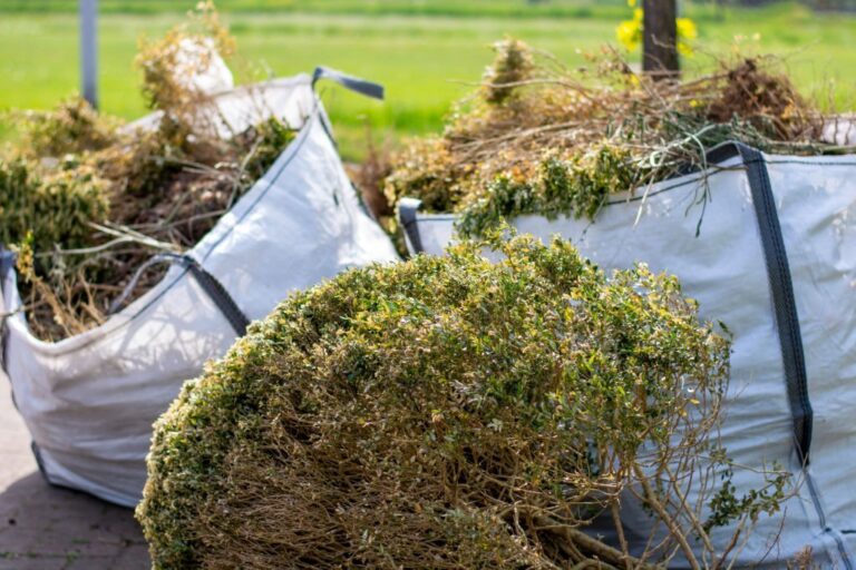 Big white bags filled with organic green garden waste after gardening 768x512