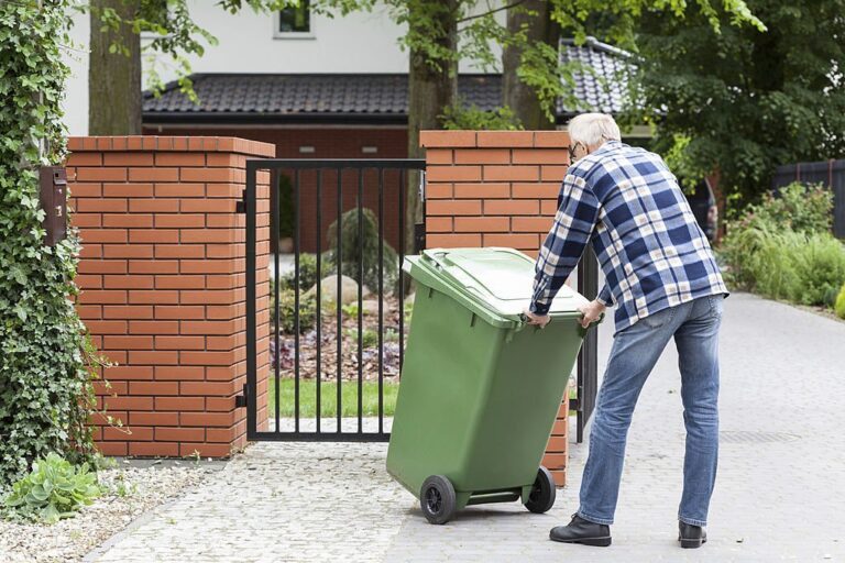 Man is pushing wheeled dumpster 768x512