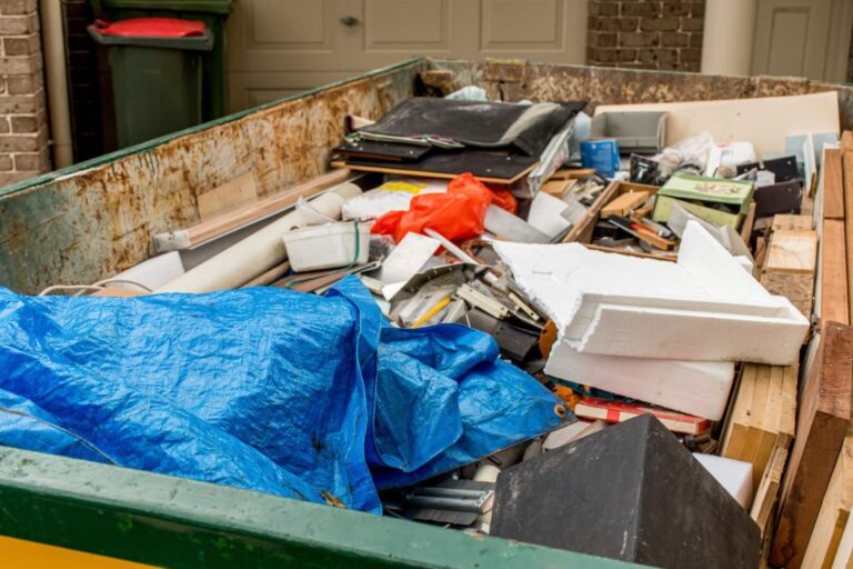 Skip bin full of household waste rubbish on the frond yard 768x512