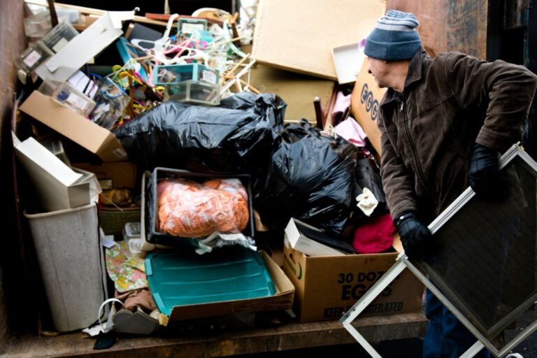 Workman loading junk in dumpster 768x512