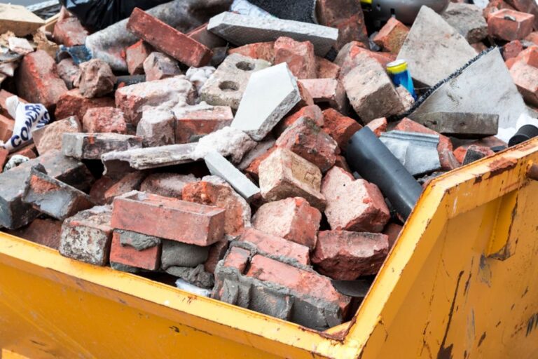 Yellow metal skip full of old bricks 768x512